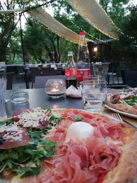 Pizza e bicchieri su un tavolo della terrazza al tramonto, sotto le luminarie