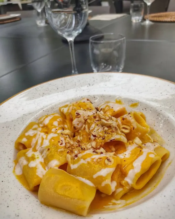 Un piatto di pasta con crema gialla e croccante sopra