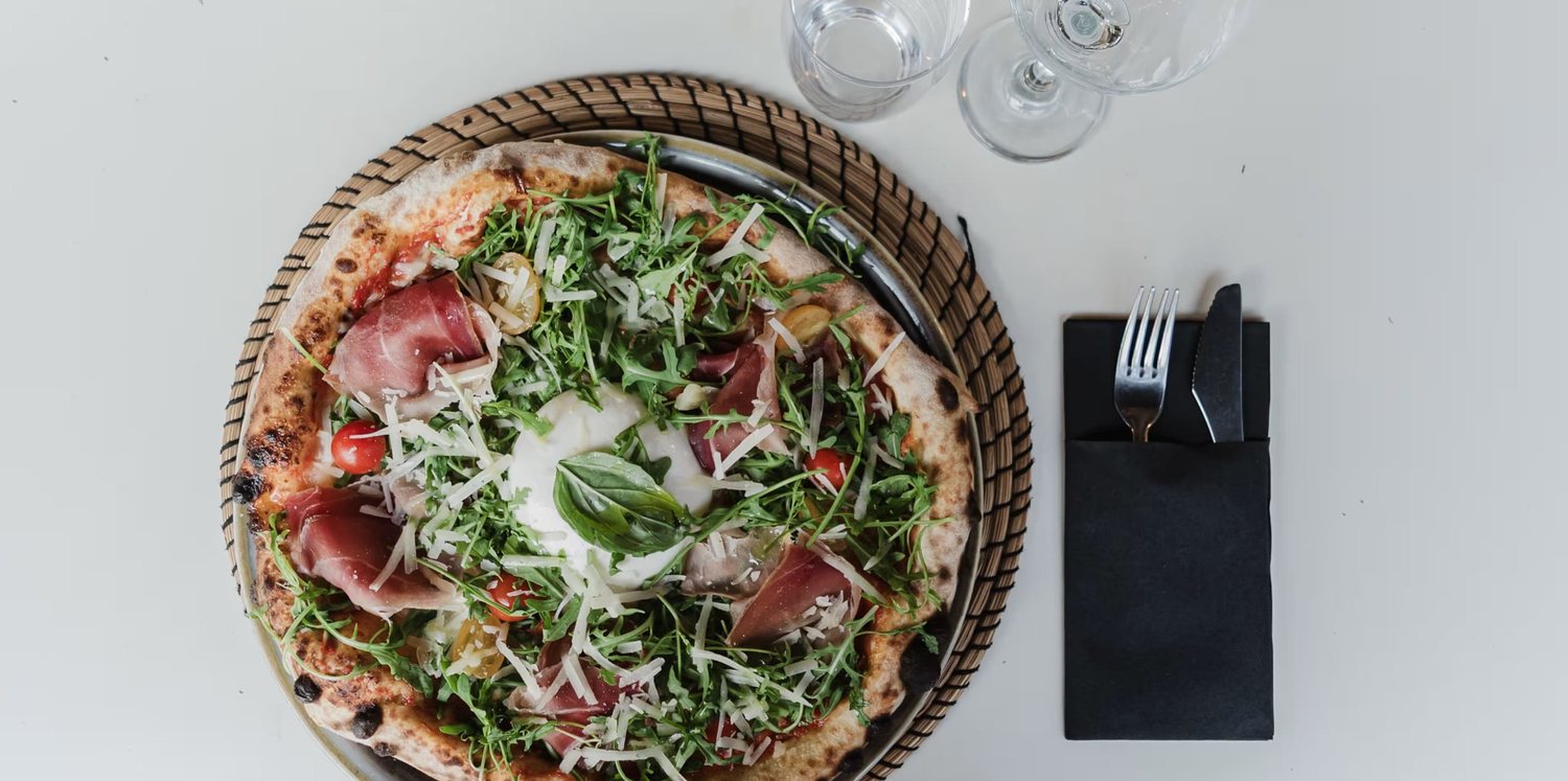 Un tavolo condiviso con più pizze e una caraffa di vino