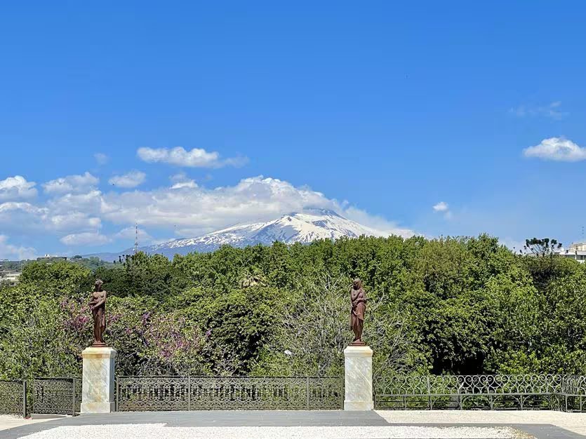 Snow-capped Etna seen from the Villa Bellini garden, beyond the statues and the iron railing